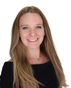 Professional headshot of Emma Knutty, Policy Analyst at Ferfox Strategies. She is smiling and facing the camera, with long light brown hair worn down, wearing a dark top, a delicate necklace, and small earrings, against a plain light background.